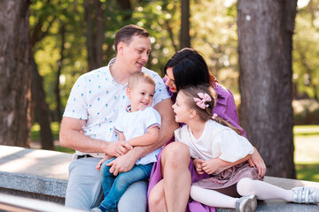 Happy young family with two kids walking in the park