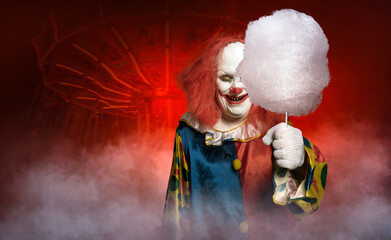 eerie clown in front of a fun fair tries to lure with cotton candy