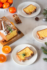 Winter bakery. Citrus loaf moist cake decorated with tangerines, rosemary, spices and sugar powder. Merry Christmas and Happy New Year concept.