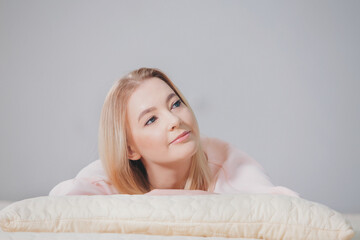 Fototapeta premium the blonde in pink is lying on the floor. the girl smiles. beauty and health of the face, hair, and skin. copy space
