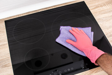 Cleaning a black electric induction cooktop. Close up