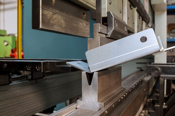 Bending sheet metal on a hydraulic machine at the factory. Bend tools, press brake punch and die. Close-up.