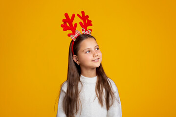 Child waiting for Santa Claus. Beautiful little girl with horns in sweater looks up at empty space