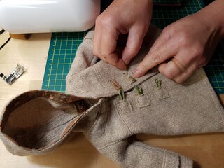 The seamstress sews doll clothes