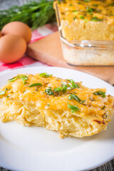 Delicious potato casserole with egg and cheese on a gray wooden background