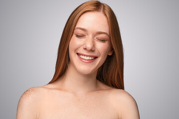 Freckled woman laughing with closed eyes