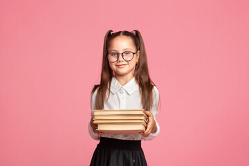 Nerd and smart kid. Cute little schoolgirl in glasses and uniform holds books