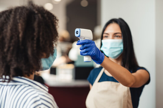 Female beauty master checking client using infrared thermometer