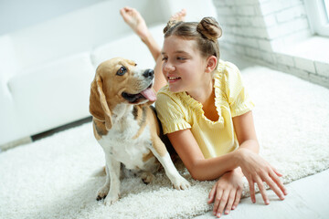 Child with a dog. Teenage girl with a beagle dog at home. High quality photo.