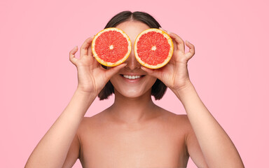 Happy Asian woman with grapefruits near eyes
