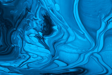 Monochrome blue marble background.Mixed nail polishes,make up concept.Beautiful stains of liquid...