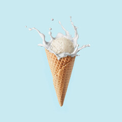 Fresh natural ice-cream in a corn with milk splash against pastel blue background.