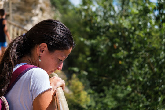 Close Up Of Young Woman Leaning On A Handrail And Looking Down From High Rock