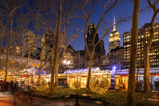 New York City, NY, USA - December 11, 2018: Bryant Park Winter Village (Christmas Market) in evening with the Empire State Building (National Historic Landmark). Midtown, Manhattan