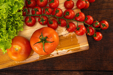 Cherry tomatoes and lettuce leaves and tomatoes with drops of water on wood on a rustic wood table, white background, selective focus.
