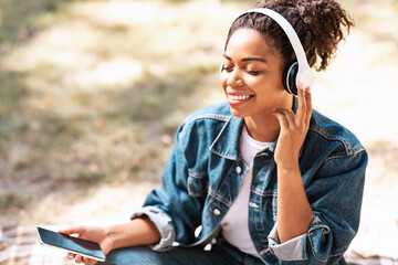 Happy African Woman In Headphones Enjoying Music Relaxing Sitting Outdoor