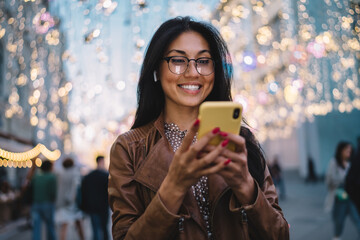 Cheerful millennial blogger enjoying mobile networking during travel vacations for visiting new...