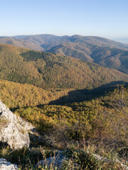 Scenic view from the slope of the Kozara mountain overgrown with forest during a sunny day against the blue sky.