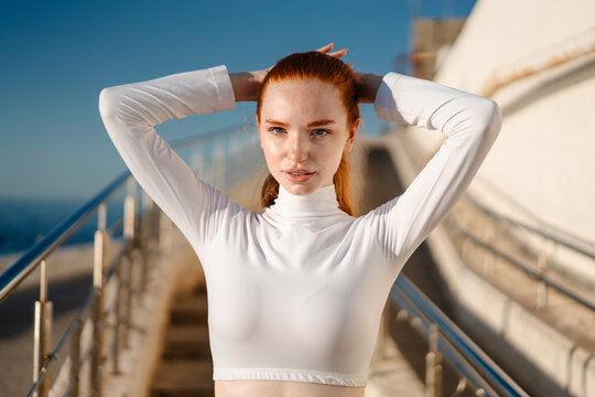 Image of redhead young sportswoman looking at camera while working out
