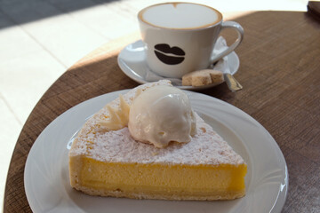 Delicious Serbian breakfast - a cup of hot cappuccino with milk foam and sweet lemon pie with vanilla ice-cream