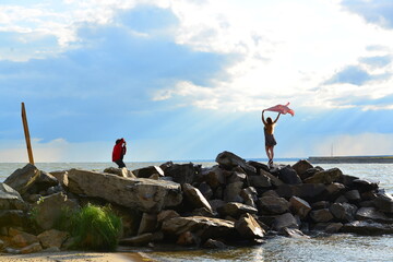 A model with a developing jacket over her head against the backdrop of the sea.