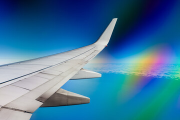 Flying towards New Zealand with the aircraft wing on the left, views of the ocean and clouds below, the rainbow glare from a polarizing filter against the aircraft window.