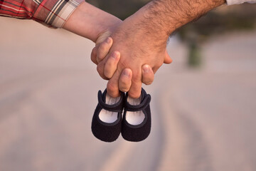 Expecting parent's hands holding baby shoes