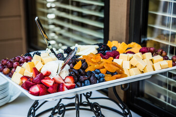 appetizer plate with fruit and cheese outside on white tablecloth
