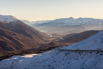 Views of snow covered mountains looking towards Frankton and Queenstown from the Crown Ranges just before dusk during winter. Arrow Junction, New Zealand.