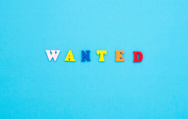 Search for employees to work. The word WANTED in colored wooden letters on a blue background.