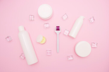 Body and skin care, cosmetology. White plastic containers for cosmetics and creams and mesoroller. Ice cubes, free space for text, top view.