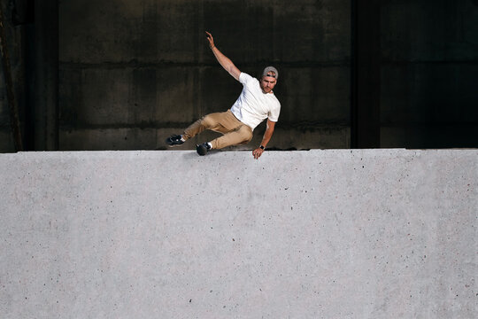 Young strong parkour and freerunning athlete jumping over the wall in urban environment. Copy space. Extreme sport and outdoor training concept