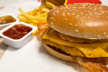 Lunch fast food chicken burger with bacon with potato fries and sauces. junk food delivery, selective focus.