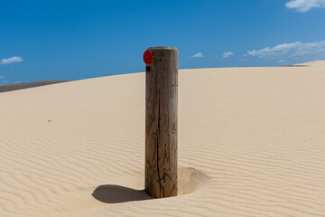 A single timber post with a reflector among sand dunes. - Powered by Adobe