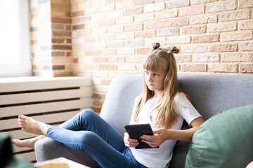 Teenage schoolgirl doing homework with digital tablet at home. A child using gadgets to study. Education and distance learning of children. Homeschooling during quarantine. Stay home fun.