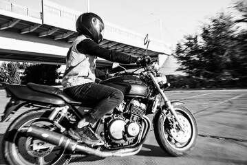 Man rides a motorcycle in the city.Motorcyclist riding a bike during the day on the road.Black and white photo