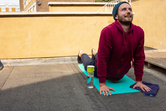 Happy Young Guy Doing Yoga Outside Wearing Comfortable Outfit In A Sunny Autumn Day.
