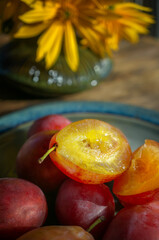 Ripe large juicy red plum lies in a beautiful plate on a wooden rustic table. Close up