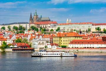 Obraz premium Lesser town (Mala Strana) cityscape with Prague Castle and cruise boat on Vltava river, Czech Republic