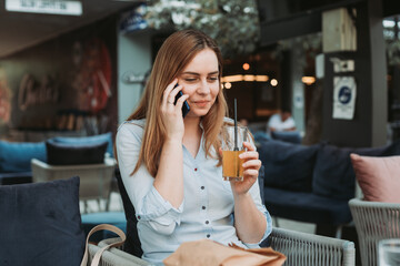 Young blonde woman talking on the phone in coffee shop