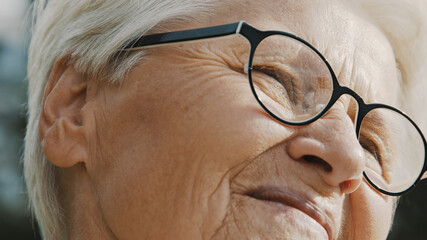 Old woman face epression while enjoying breeze on the sunny autumn day. High quality photo