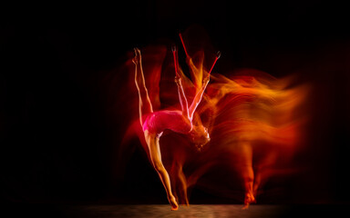 Bright. Young flexible girl isolated on black studio background in mixed light. Female rhythmic...