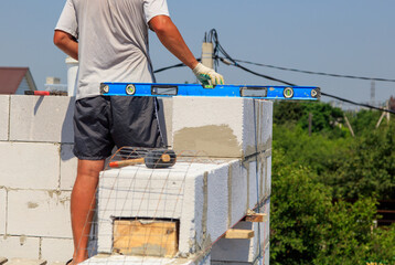 A worker builds the walls of a house from aerated concrete bricks.