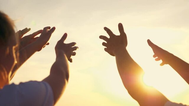 People's hands reach for the sun at sunset. Happy family together. Teamwork. A cry for help, People together in prayer turn to the sun.