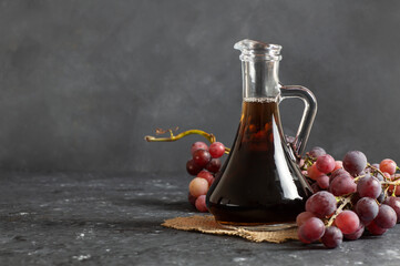 Glass bottle of organic black grape balsamic vinegar made from fermented fresh grapes. Healthy organic food black fruit, selective focus