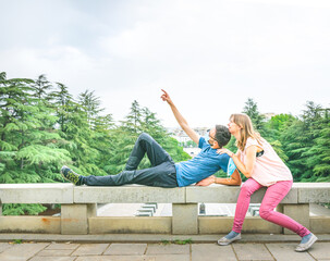 Young playful couple messing around out of joy with male person mask on showing his finger up....