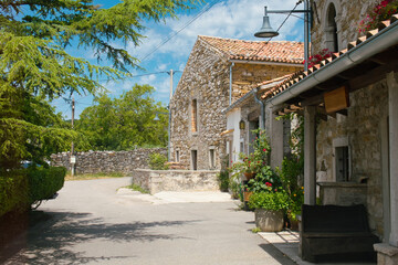 Fototapeta na wymiar A beautiful street, pile of firewood and old historic houses decorated with flower pots in the medieval town of Roc in Istria, Croatia