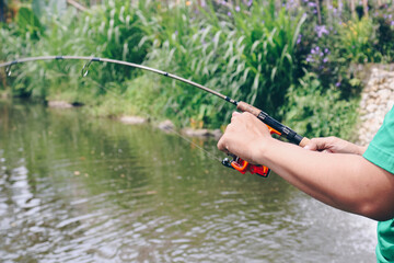 Close up of spinning with the fishing reel in the hand, fishing hook on the line with the bait in...