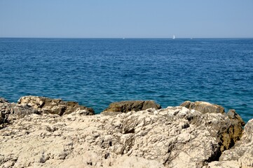 Fototapeta na wymiar sea coast with blue calm sea, rocks, and blue sky in the background