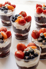 Festive cake for the birthday. Сakes with cream and berries. Desserts for adults and children on table. Festive cupcakes with chocolate and berries. Vertical photo.